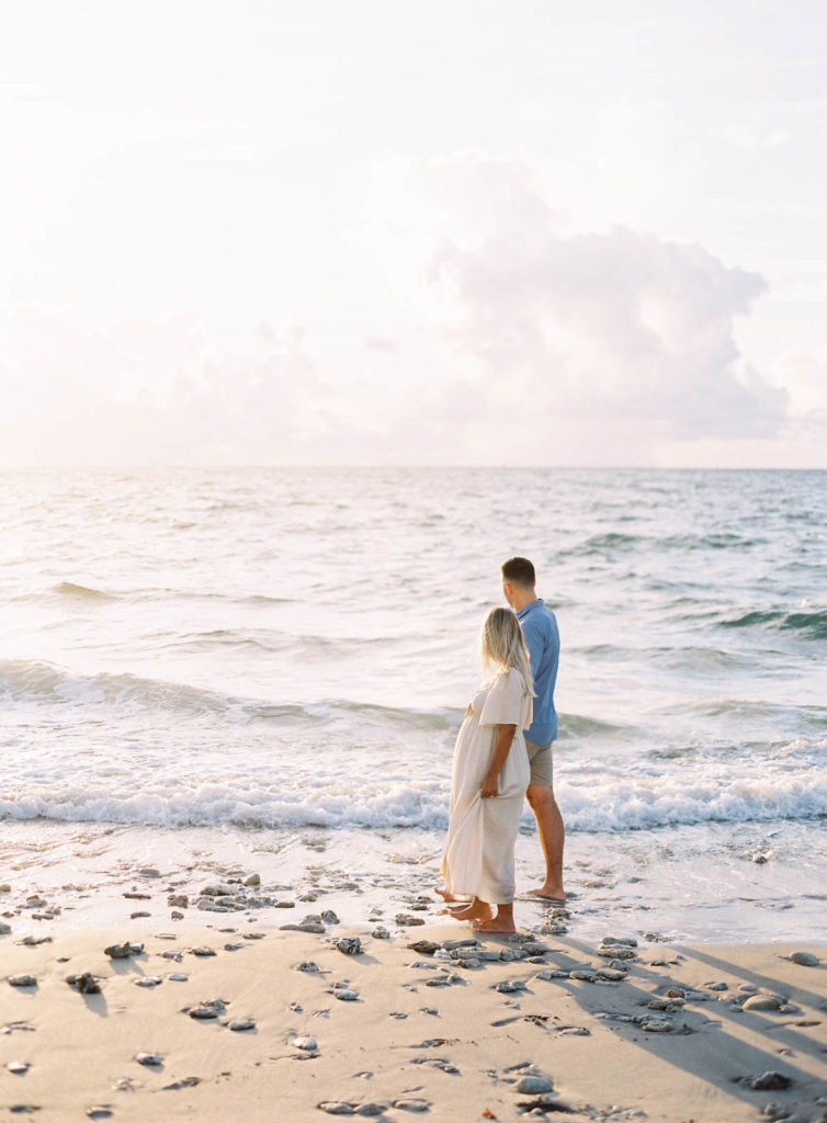 Expecting couple walking along Fort Lauderdale Beach at sunrise during their maternity photo session.